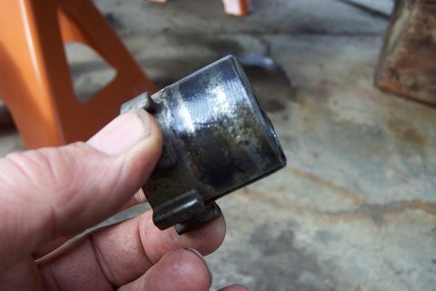 1990 Ford Bronco - Close-up of a greasy ball joint part being held by a hand, with a jack stand visible.
