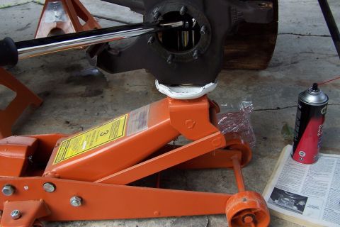 1990 Ford Bronco - Working on a vehicle's suspension part with tools and a jack.
