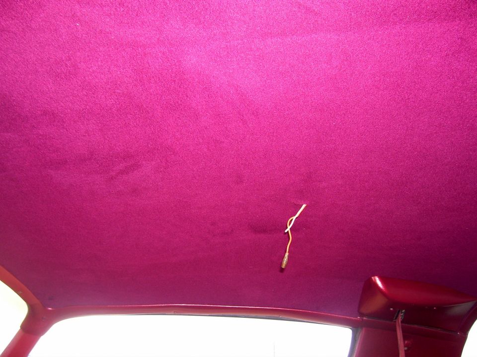 Car interior headliner with pink upholstery and exposed wiring