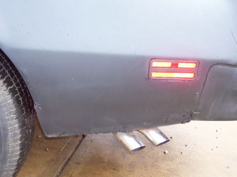 1978 Pontiac Trans Am - The rear quarter panel of a 1978 Pontiac Trans Am shows dual exhaust pipes and a lit side marker light.