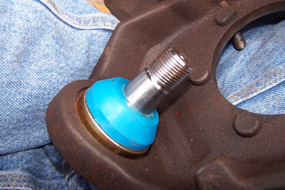 close-up of a ball joint with a blue boot and metal stud, resting on denim fabric