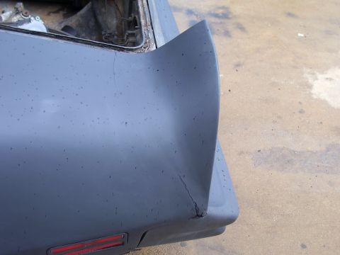 1978 Pontiac Trans Am - Rear quarter panel and spoiler of a 1978 Pontiac Trans Am showing cracks and primer coat.