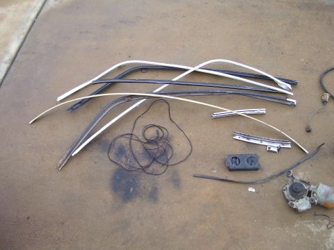 1978 Pontiac Trans Am - Various car trim pieces and a windshield wiper motor are displayed on a concrete surface.