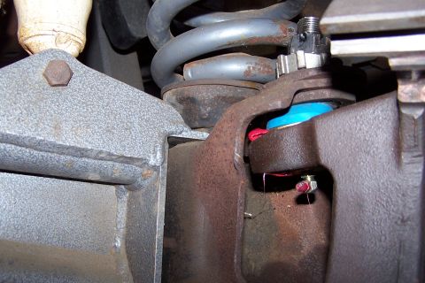 1990 Ford Bronco - Close-up view of a vehicle's ball joint assembly, showing a blue boot and red grease.