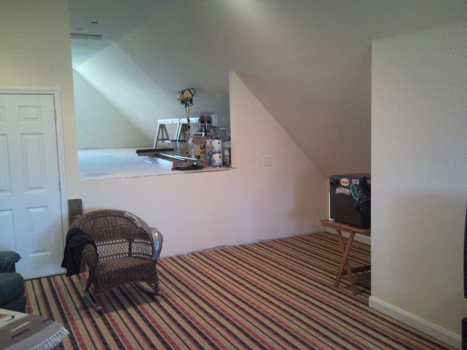 Attic bonus room with striped carpet, wicker chair, and unfinished storage area