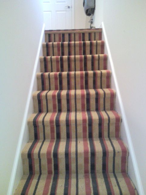 1992 Ford Bronco - A set of stairs is covered in a carpet with vertical stripes of tan, red, and navy blue.