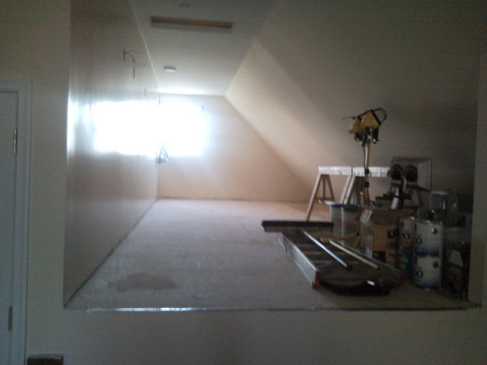 Unfinished attic room under construction with ladder and buckets