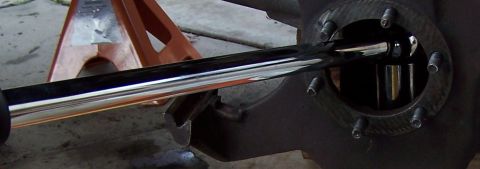 1990 Ford Bronco - A close-up view of a ball joint being serviced with a tool, with a vehicle supported by a jack stand in the background.
