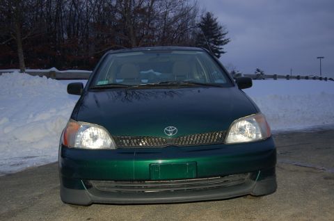 2001 Toyota Echo - Front view of a dark green sedan with a mesh grille and clear headlights, parked outdoors in a snowy environment.