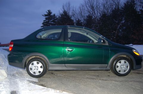 2001 Toyota Echo - Side view of a green 2001 Toyota Echo sedan parked on a road with snow on the side.