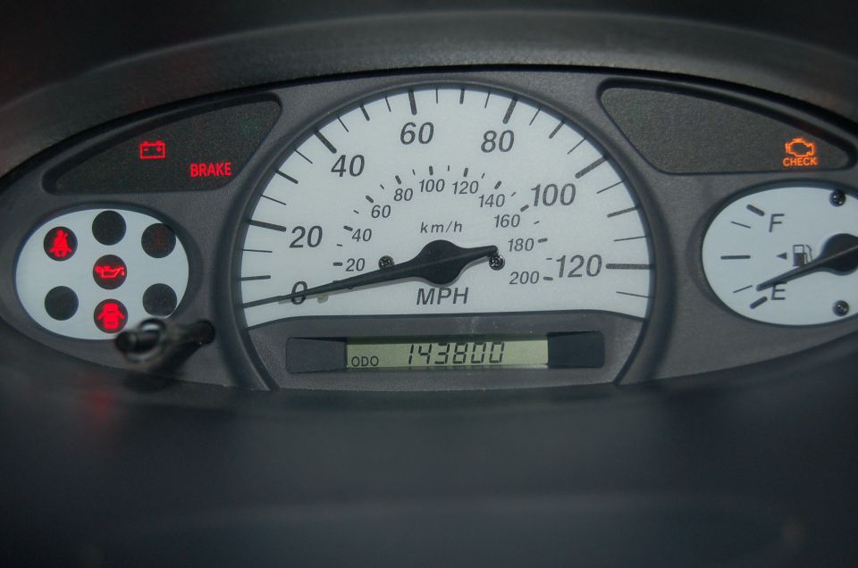White-face speedometer and fuel gauge cluster, odometer reads 143800, warning lights on