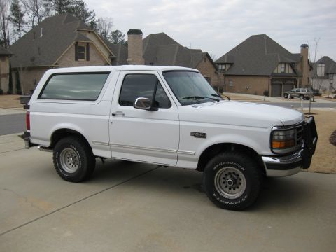 1996 Ford Bronco - A white 1996 Ford Bronco is parked in a suburban driveway with houses in the background.