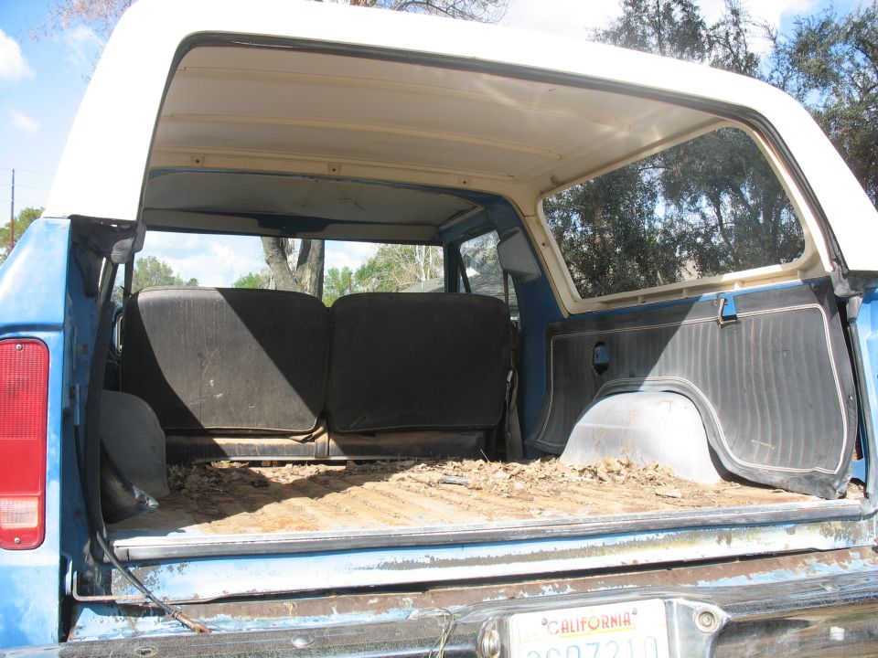 1987 Ford Bronco interior cargo area with rear seats folded down, dirt and debris on the floor