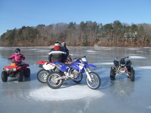 1995 Ford Mustang - Several off-road vehicles and their riders are gathered on a frozen body of water under a clear blue sky.