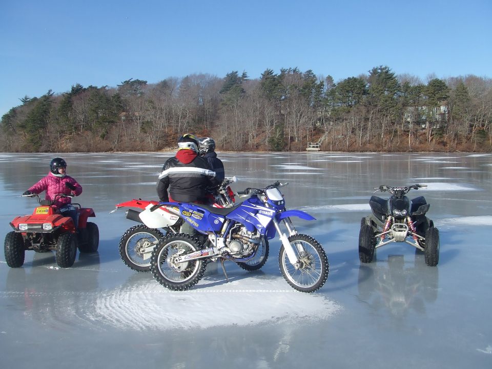Four-wheelers and dirt bikes on a frozen lake with riders