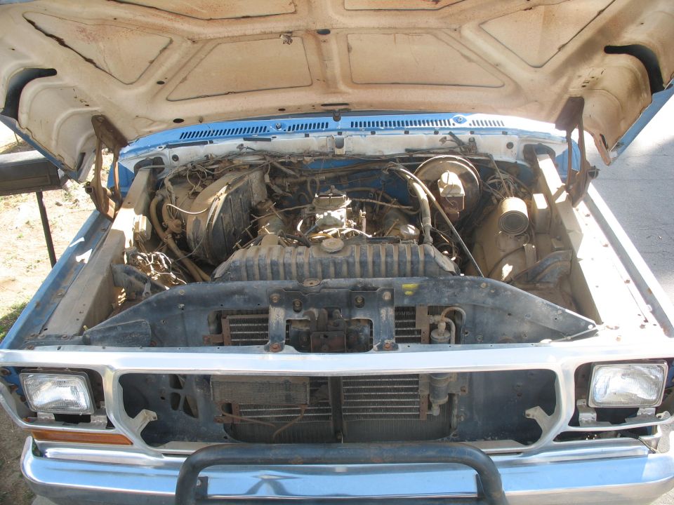 Engine bay of a blue and white truck with hood open
