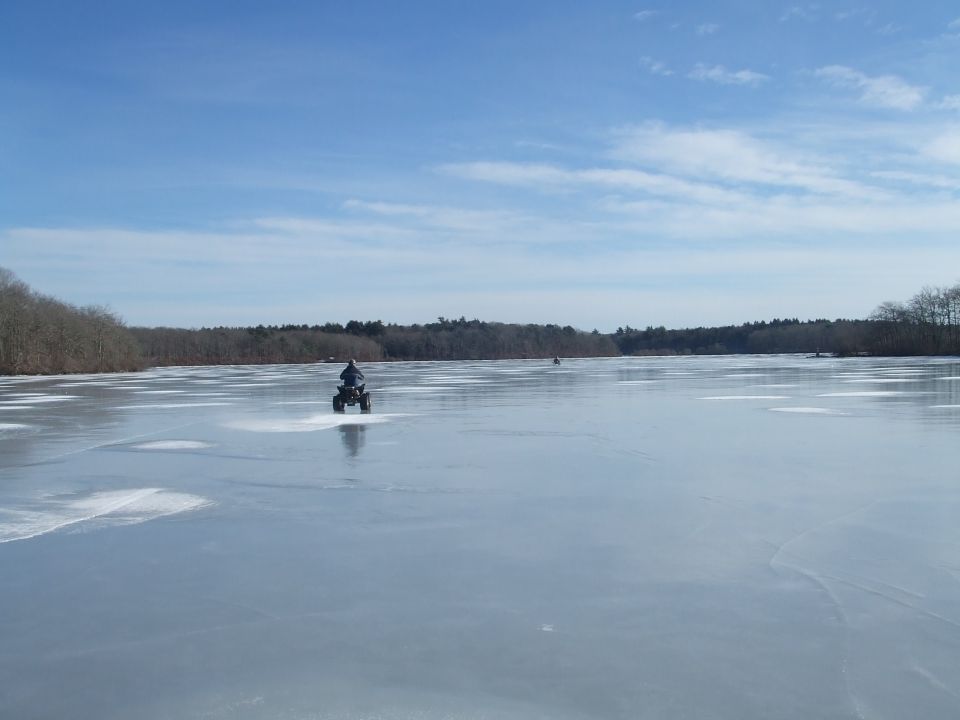 ATV on frozen lake with trees in background