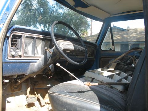 1987 Ford Bronco - Interior of an older blue pickup truck, likely from the 1970s, with a worn dashboard and steering wheel.