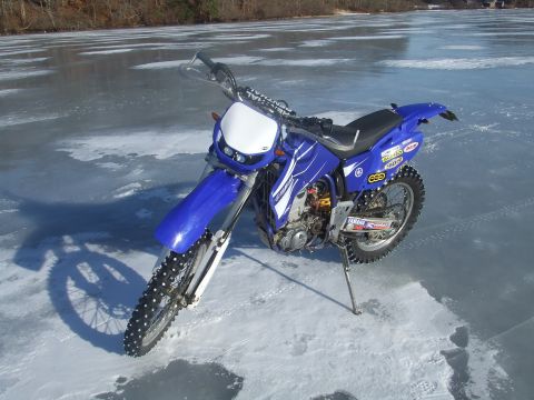 1995 Ford Mustang - A blue Yamaha dirt bike with studded tires sits on a frozen lake, ready for winter riding.