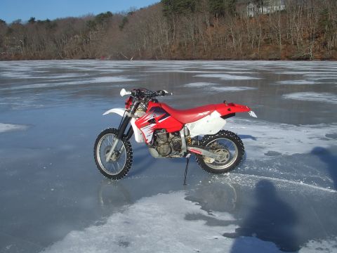 1995 Ford Mustang - A dirt bike sits on a frozen body of water with trees in the background.
