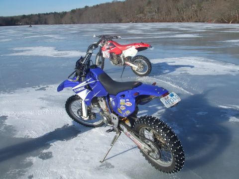 1995 Ford Mustang - Two dirt bikes, a blue Yamaha and a red Honda, are parked on a frozen lake, ready for ice riding.
