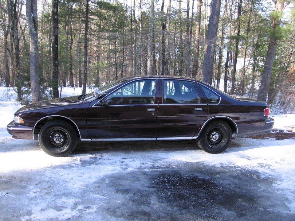Dark sedan parked on a snowy, icy surface with trees in the background