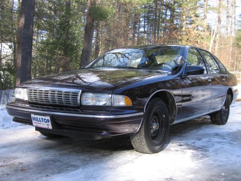 1991 Ford LTD Crown Victoria - This dark sedan, likely a 1991 Chevrolet Caprice, is parked outdoors on a snowy day with trees in the background.