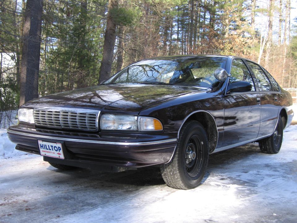 Dark sedan with a chrome grille and a "HILLTOP" license plate parked on a snowy surface
