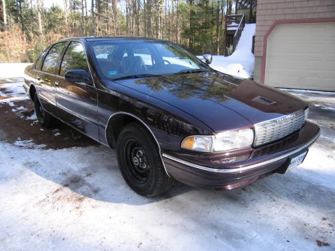 1991 Ford LTD Crown Victoria - This sedan features a prominent chrome grille and a dark purple finish, seen here in a front three-quarter perspective.