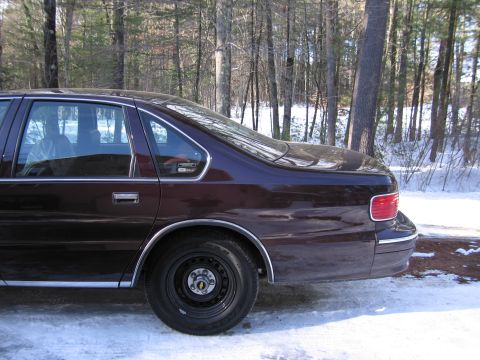 1991 Ford LTD Crown Victoria - Rear view of a dark red sedan parked in a snowy, wooded area.