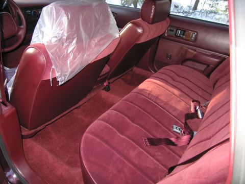 1991 Ford LTD Crown Victoria - Interior view of a car with maroon velour seats and a plastic-covered front seat.