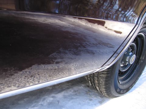 1991 Ford LTD Crown Victoria - Side view of a car's lower body panel and wheel, partially covered in snow.