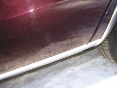 1991 Ford LTD Crown Victoria - Close-up of a car's lower door panel and tire, showing wear and tear.
