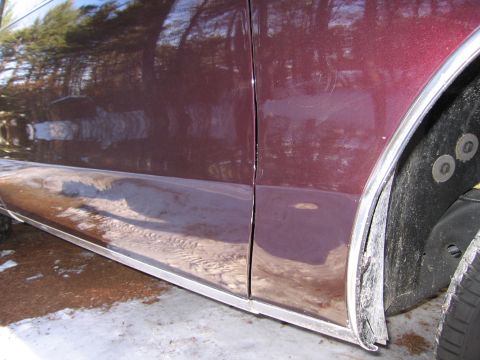 1991 Ford LTD Crown Victoria - Close-up of a maroon car's side door seam and wheel well area.