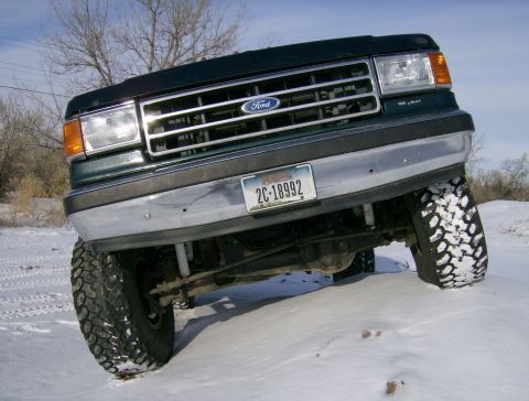 1990 Ford Bronco - A 1990 Ford Bronco drives through a snowy landscape.