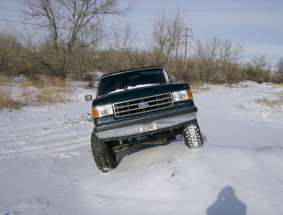 Green 1990 Ford Bronco driving in snow