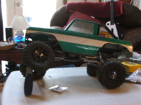1996 Ford Bronco - An RC car body, painted green and white with large off-road tires, sits on a table.