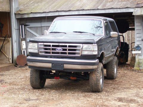 1992 Ford Bronco - This lifted Ford Bronco is parked in front of a rustic barn with its front end facing the camera.