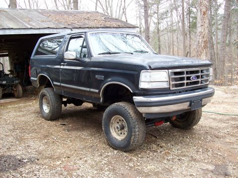 1992 Ford Bronco - This lifted 1992 Ford Bronco is parked in a gravel lot next to a rustic shed.