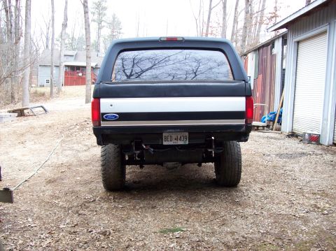 1992 Ford Bronco - Rear view of a lifted 1992 Ford Bronco parked outdoors near a garage.