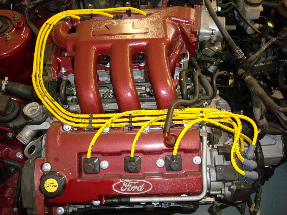 Red Ford engine with yellow spark plug wires and a Ford logo on the valve cover