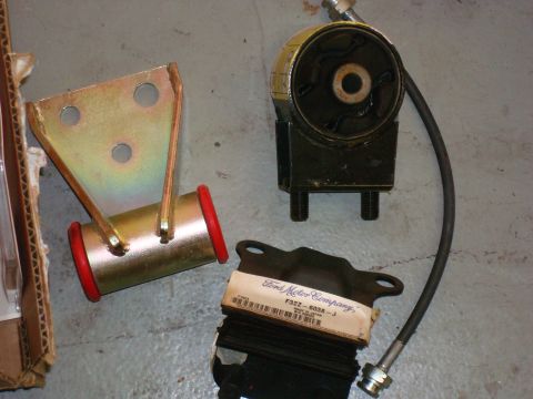 1994 Ford Probe - Several car parts, including an engine mount and suspension bushings, are laid out on a concrete floor.