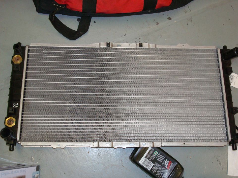Car radiator with black plastic end tanks and brass fittings. Supermotors.net logo visible