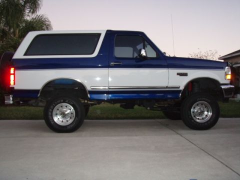 1996 Ford Bronco - Side view of a lifted 1996 Ford Bronco with a two-tone blue and white paint scheme.