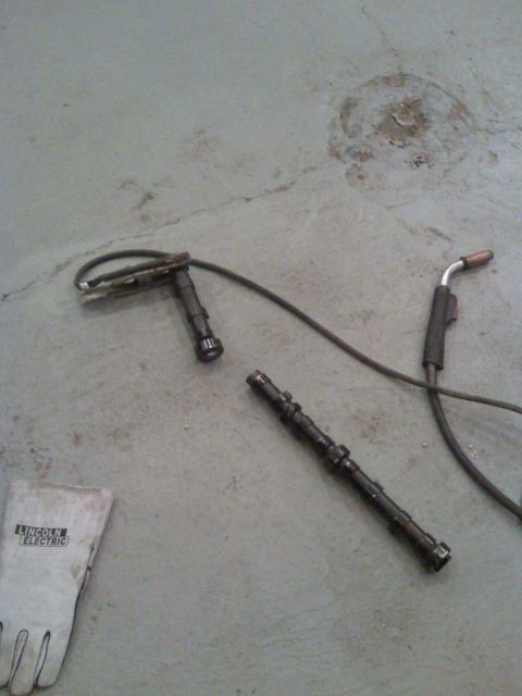 1992 Ford Bronco - Welding equipment and a camshaft lie on a concrete floor, with a Lincoln Electric glove nearby.