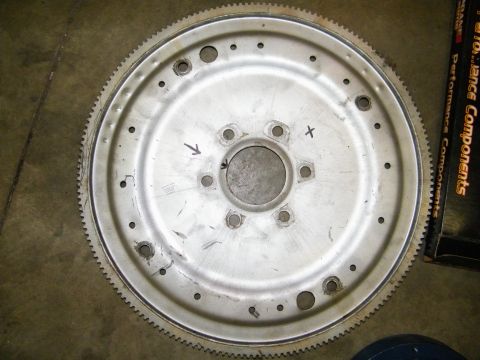 1968 Mercury Cougar - A metal flywheel with a toothed outer edge and multiple bolt holes is shown, with markings and a website logo visible.