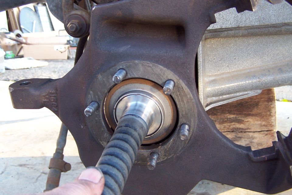 Close-up of a vehicle's wheel bearing assembly with a ribbed hose inserted