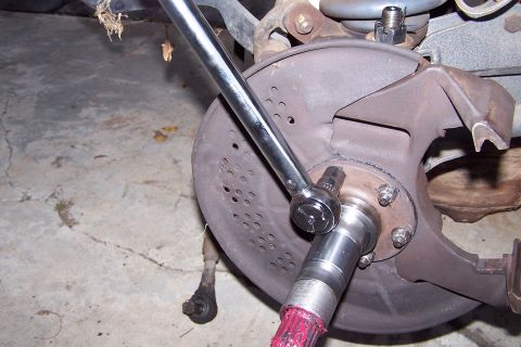 1990 Ford Bronco - Close-up of a vehicle's wheel hub assembly being worked on with a socket wrench.