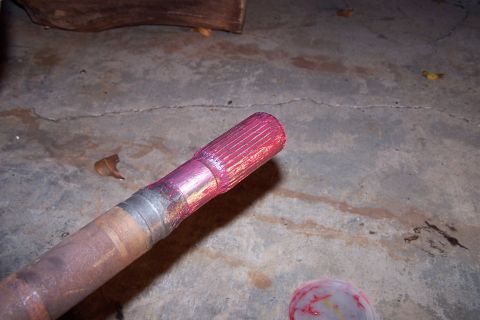 1990 Ford Bronco - A greased axle shaft is shown close-up on a concrete surface.