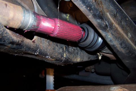 1990 Ford Bronco - Close-up of a CV axle splined shaft covered in red grease, with a black protective boot visible.